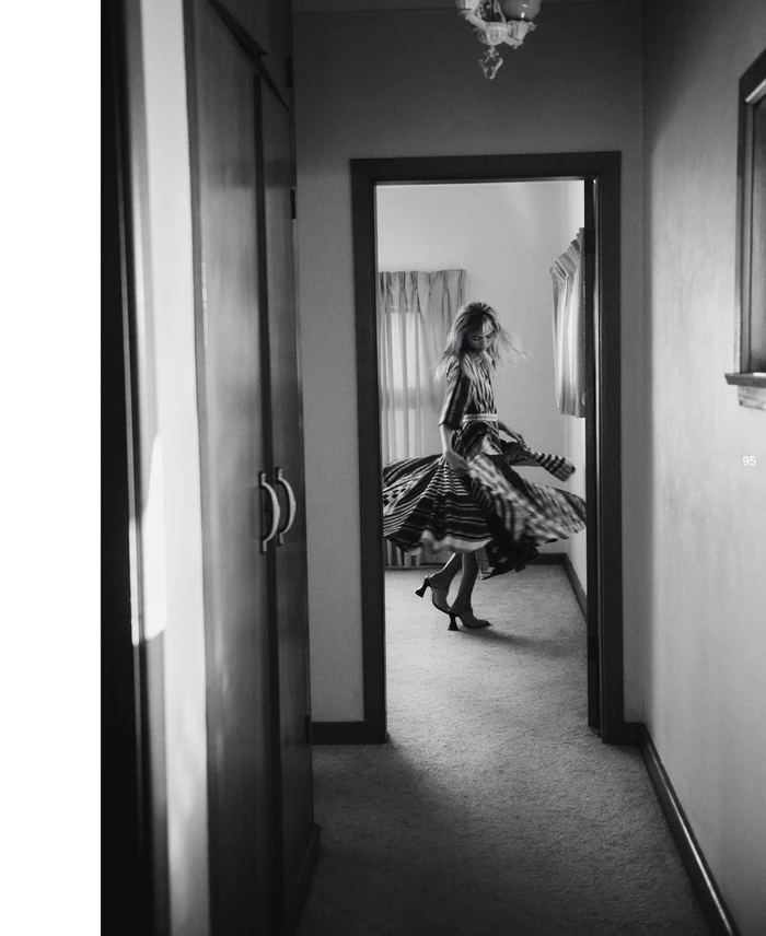 Model spinning in a patterned dress down a domestic hallway captured in monochrome