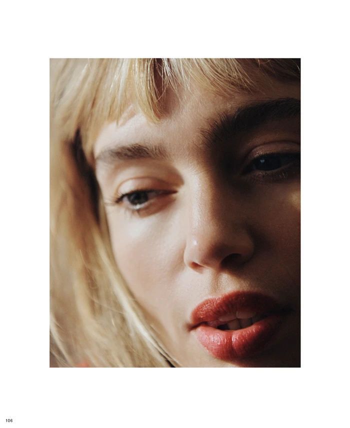 Close-up portrait of a woman with blonde bangs and red lips under soft natural light for Edition #03 Cover Story.