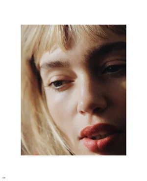 Close-up portrait of a woman with blonde bangs and red lips under soft natural light for Edition #03 Cover Story.