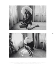 Black and white editorial image of a model wearing a large feathered hat and dark jacket kneeling on a carpeted floor.