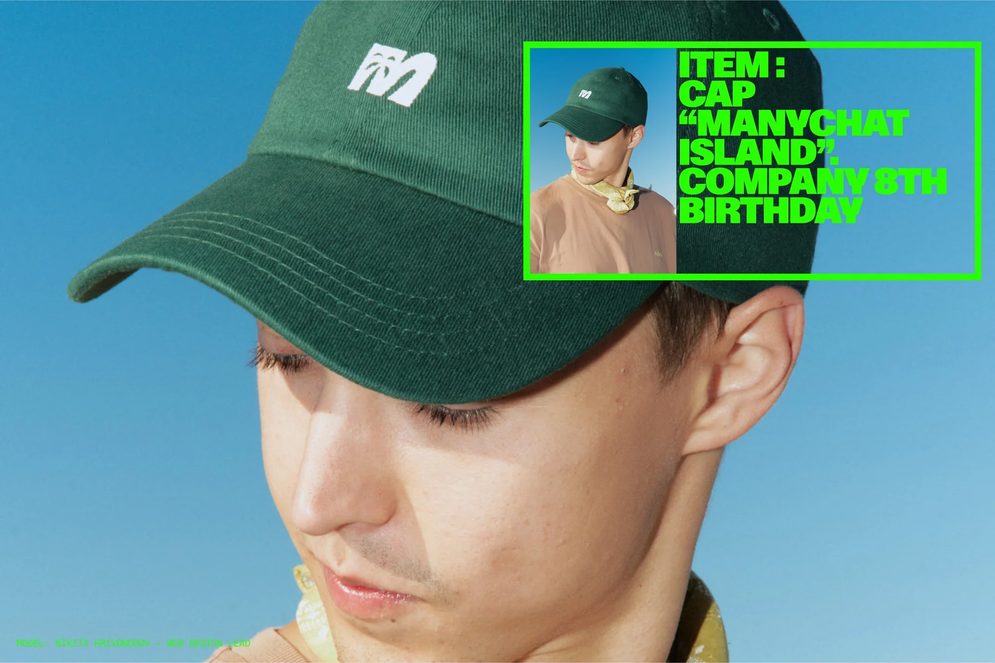Close-up of a person wearing a green baseball cap with a white logo against a clear blue sky, showcasing a casual fashion style.