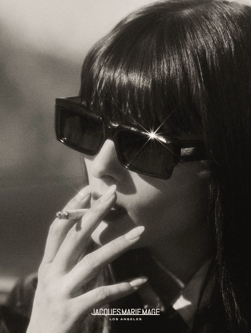 Adult woman with sunglasses smokes a cigarette in a close-up portrait. Jacques Marie Mage Los Angeles brand is visible at the bottom.