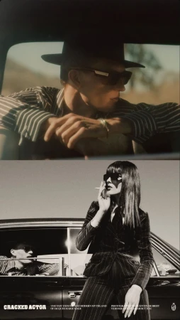 Fashion editorial shot featuring a man in a striped shirt and hat inside a car, with a woman in a pinstripe suit leaning on the car.