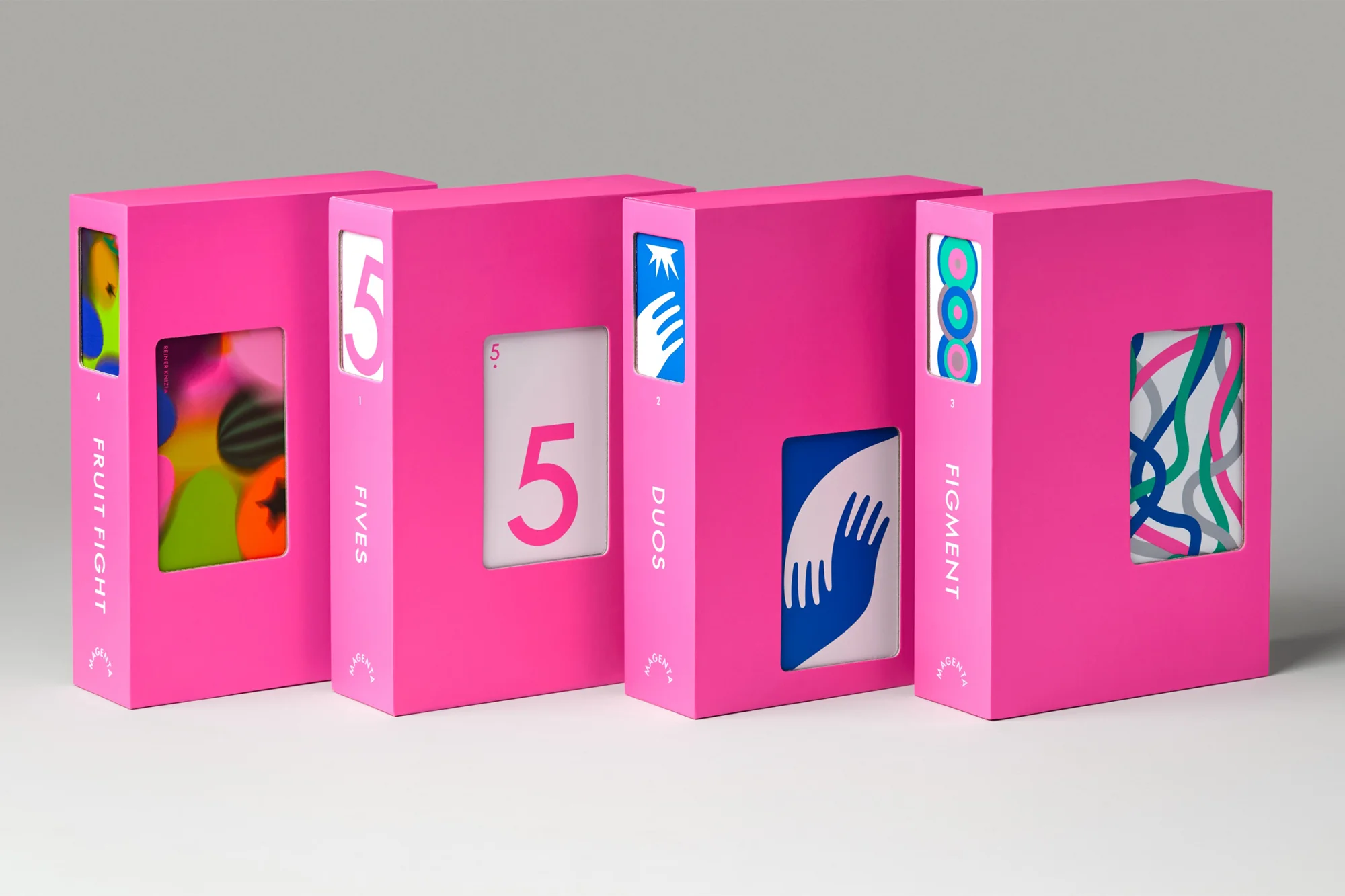 Four brightly colored decks of playing cards are lined up side-by-side against a neutral background in a studio shot.