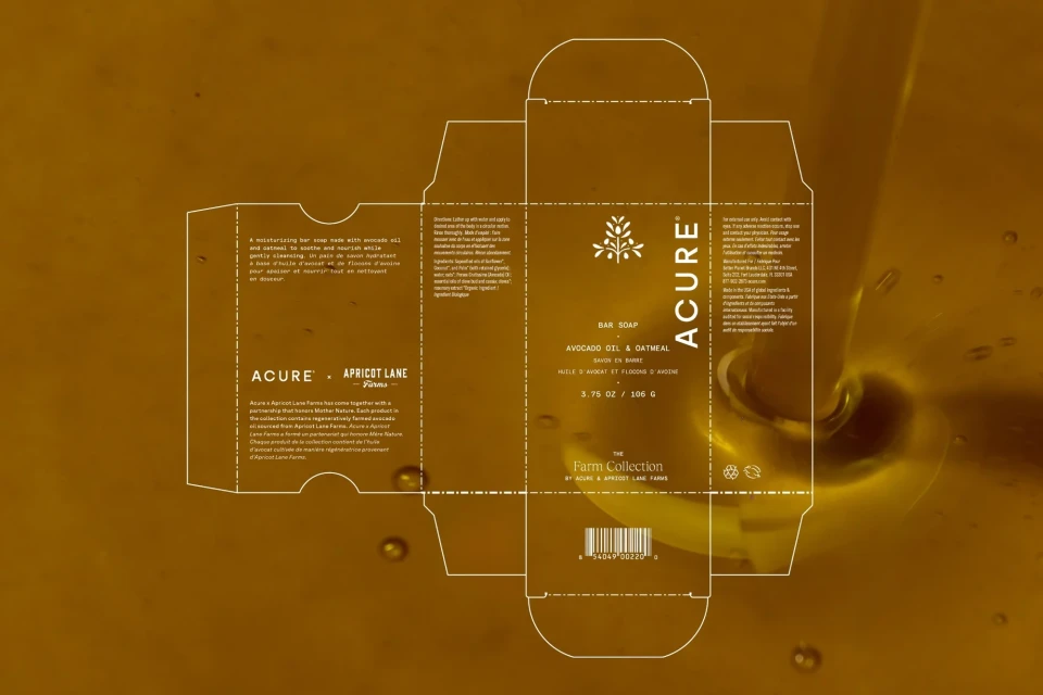 Soap box packaging with Acure brand displayed on a brown background with falling honey. Marketing materials and branding.