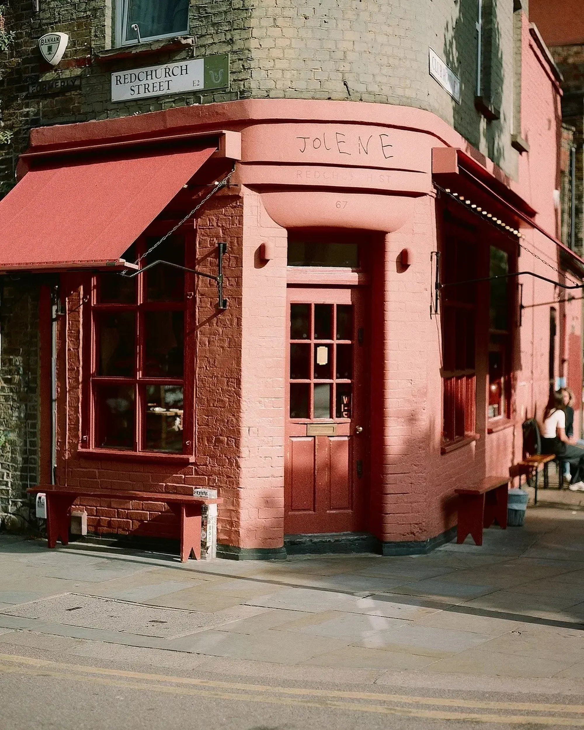 Exterior view of Jolene's restaurant, a corner building with red awnings and a brick facade, located on Redchurch Street.