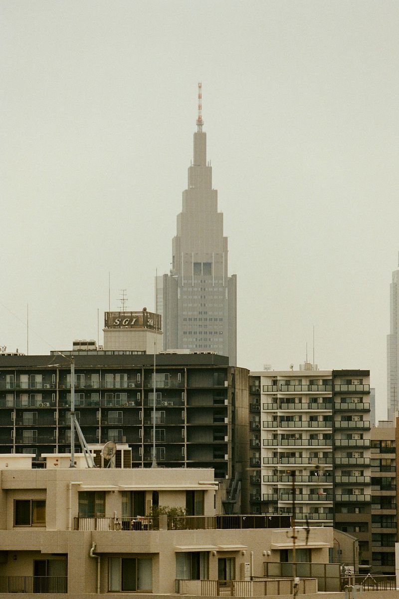 Cityscape of Tokyo, Japan featuring modern architecture and skyscrapers under an overcast sky with apartment buildings in the foreground.