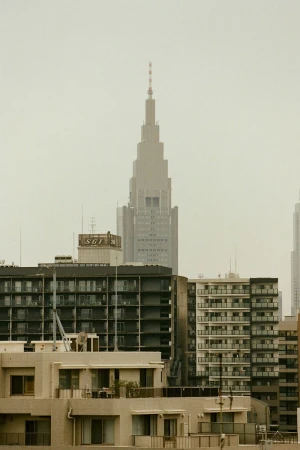 Skyscraper rising above a dense urban cityscape with apartment buildings under an overcast sky.