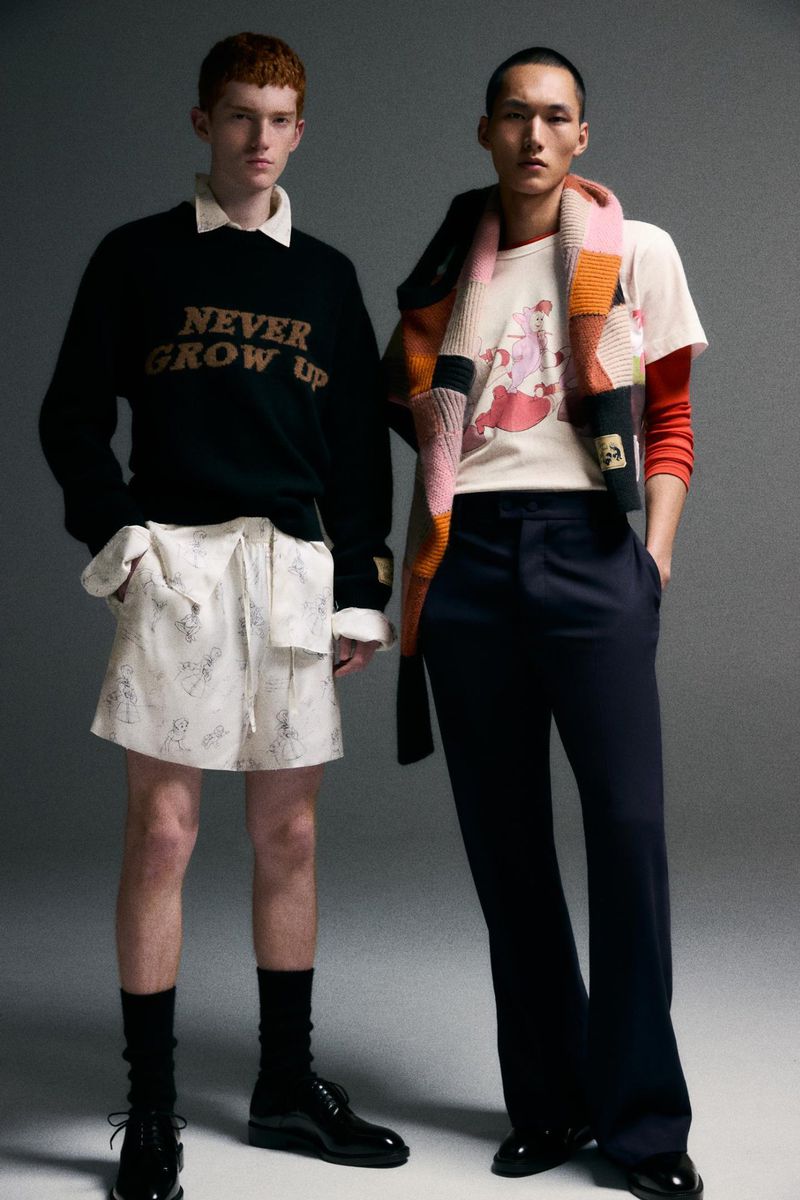 Two male models posing against a grey studio backdrop for Zara Man x Disney, wearing character-printed apparel and layered knitwear.