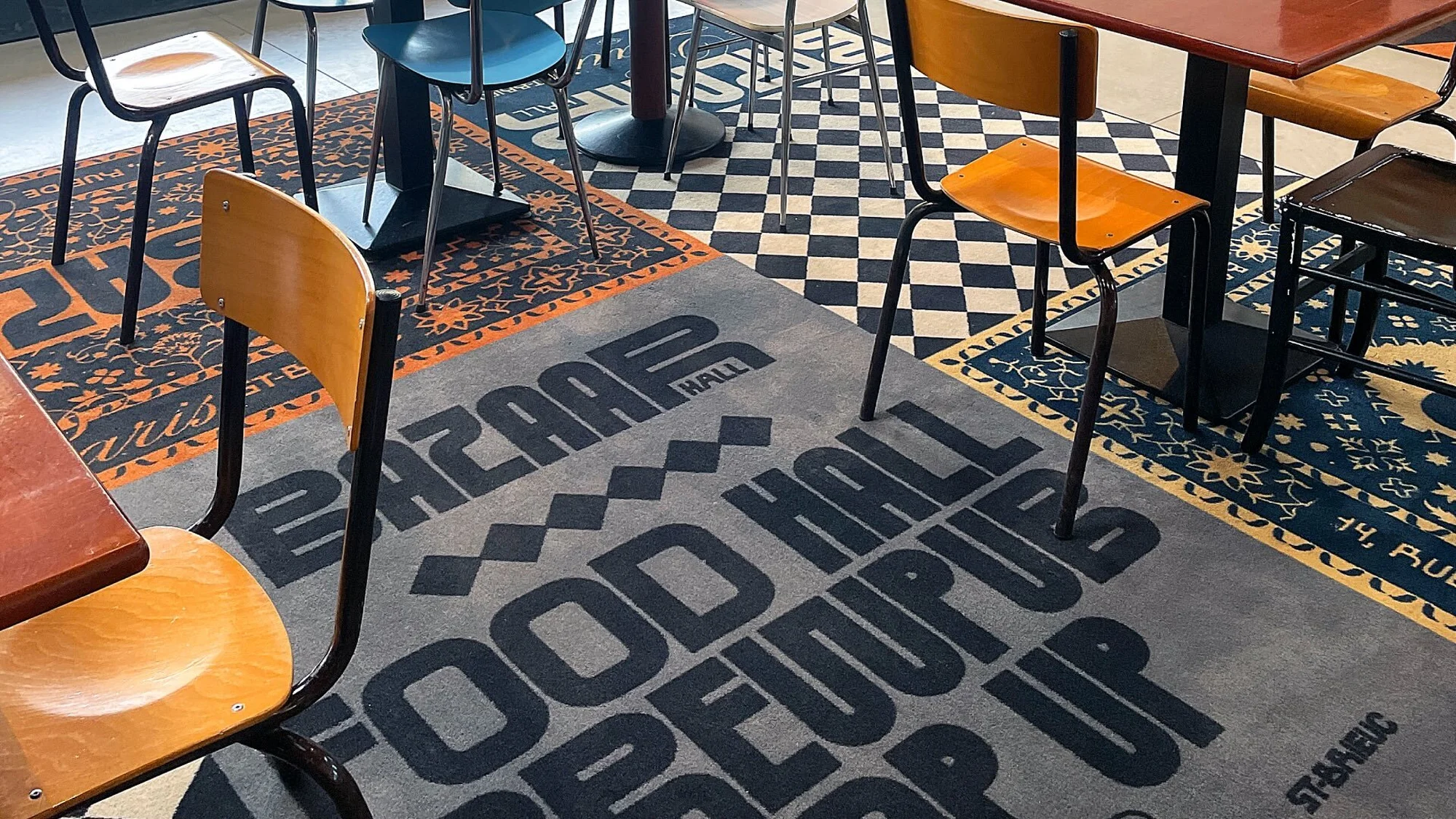Several chairs are situated on an interior floor covered in patterned rugs and tiles, creating a mix of textures and visual interest.
