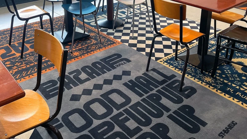 Several chairs are situated on an interior floor covered in patterned rugs and tiles, creating a mix of textures and visual interest.