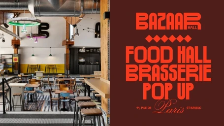 Interior of Bazaar Hall food hall featuring restaurant seating, industrial ductwork, and bold red graphic branding on a dark brown panel.