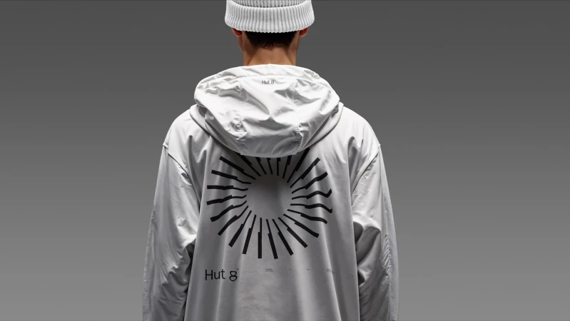 Back view of a person wearing a white hooded jacket with a geometric design, paired with a matching hat against a grey background.