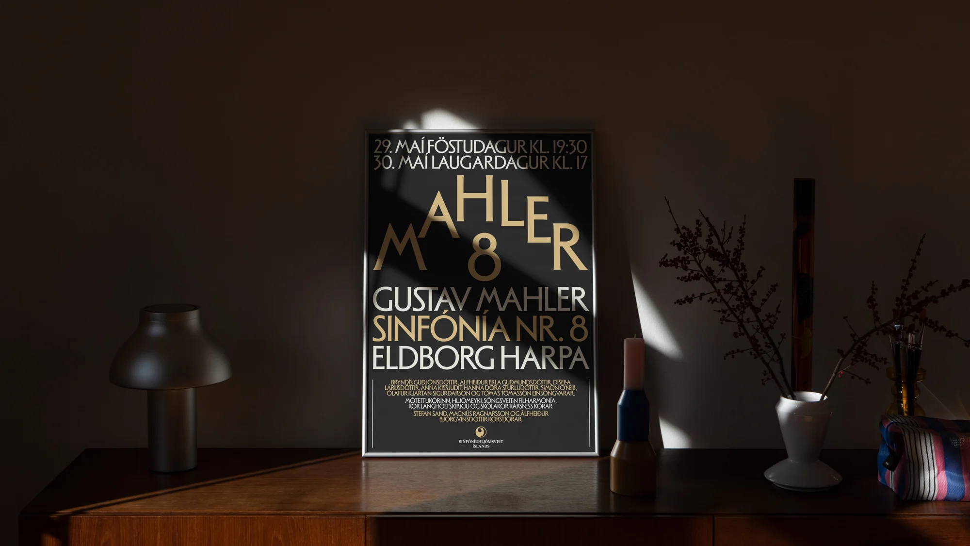 Poster featuring 'Mahler M 8' on a dark background, displayed on a wood dresser with lamp and vase in a dimly lit room.