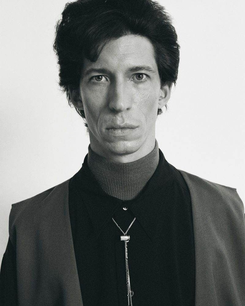 Monochrome portrait of an adult male in a shirt, vest, and bolo tie against a white background in a studio setting.