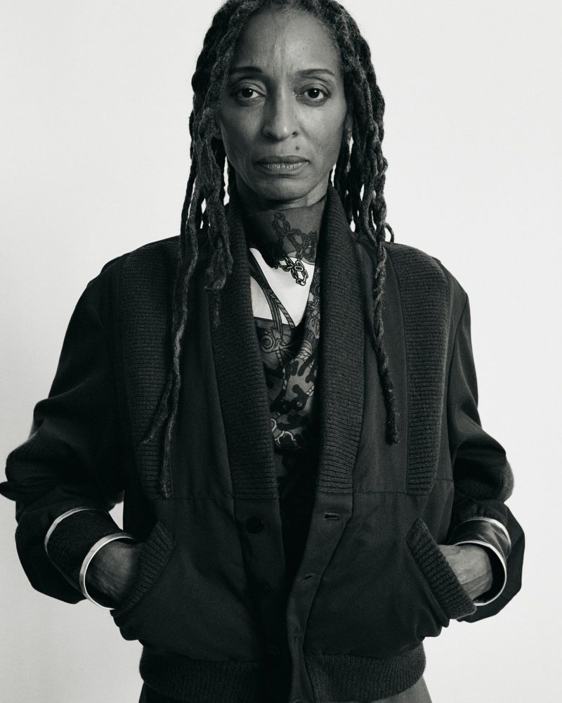 Portrait of mature Black woman in dark cardigan and silver bracelets against white backdrop, showcasing natural style and elegance.