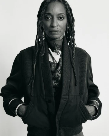 Portrait of mature Black woman in dark cardigan and silver bracelets against white backdrop, showcasing natural style and elegance.