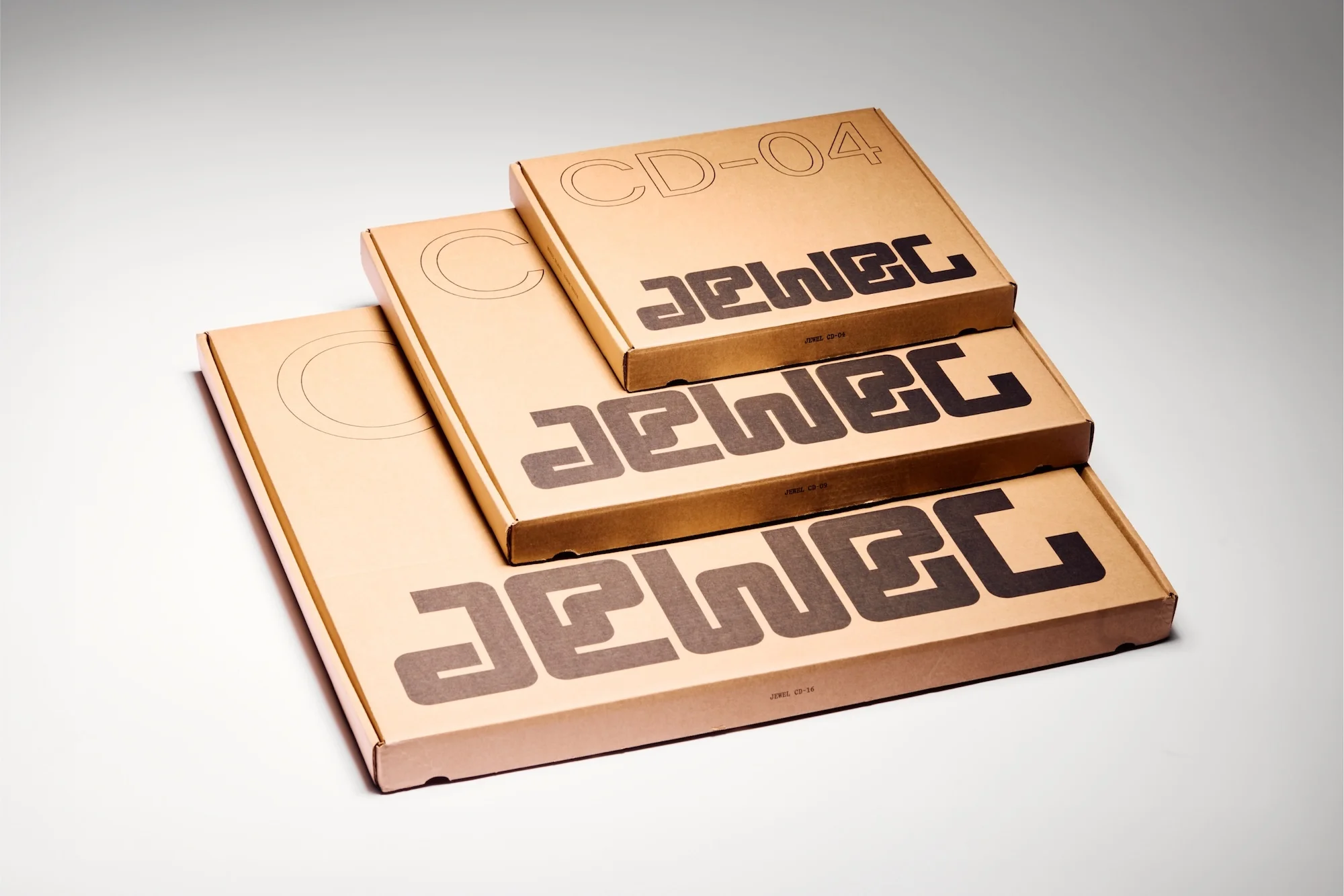 Three cardboard boxes of decreasing size are stacked on top of each other, featuring the brand name 'JEWEC' printed in bold sans-serif font.
