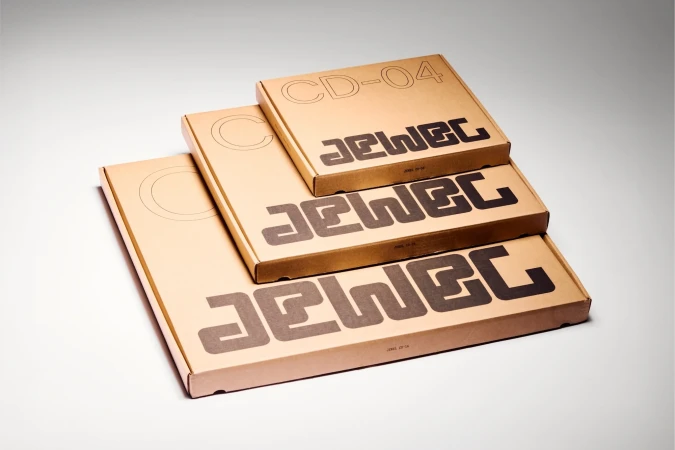 Three cardboard boxes of decreasing size are stacked on top of each other, featuring the brand name 'JEWEC' printed in bold sans-serif font.