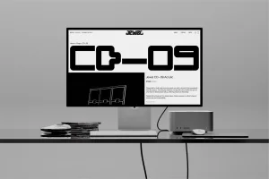 A computer monitor displaying an e-commerce website for Jewel CD-09 Acrylic sitting on a dark glossy desk in a grey studio.