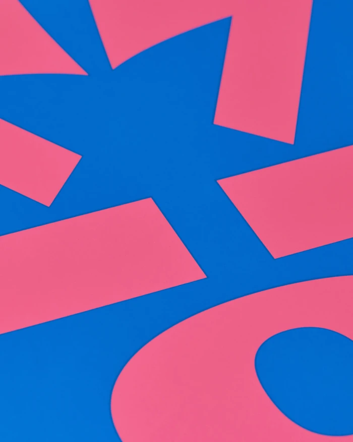 Pink geometric paper cutout shapes overlapping on a vibrant blue background