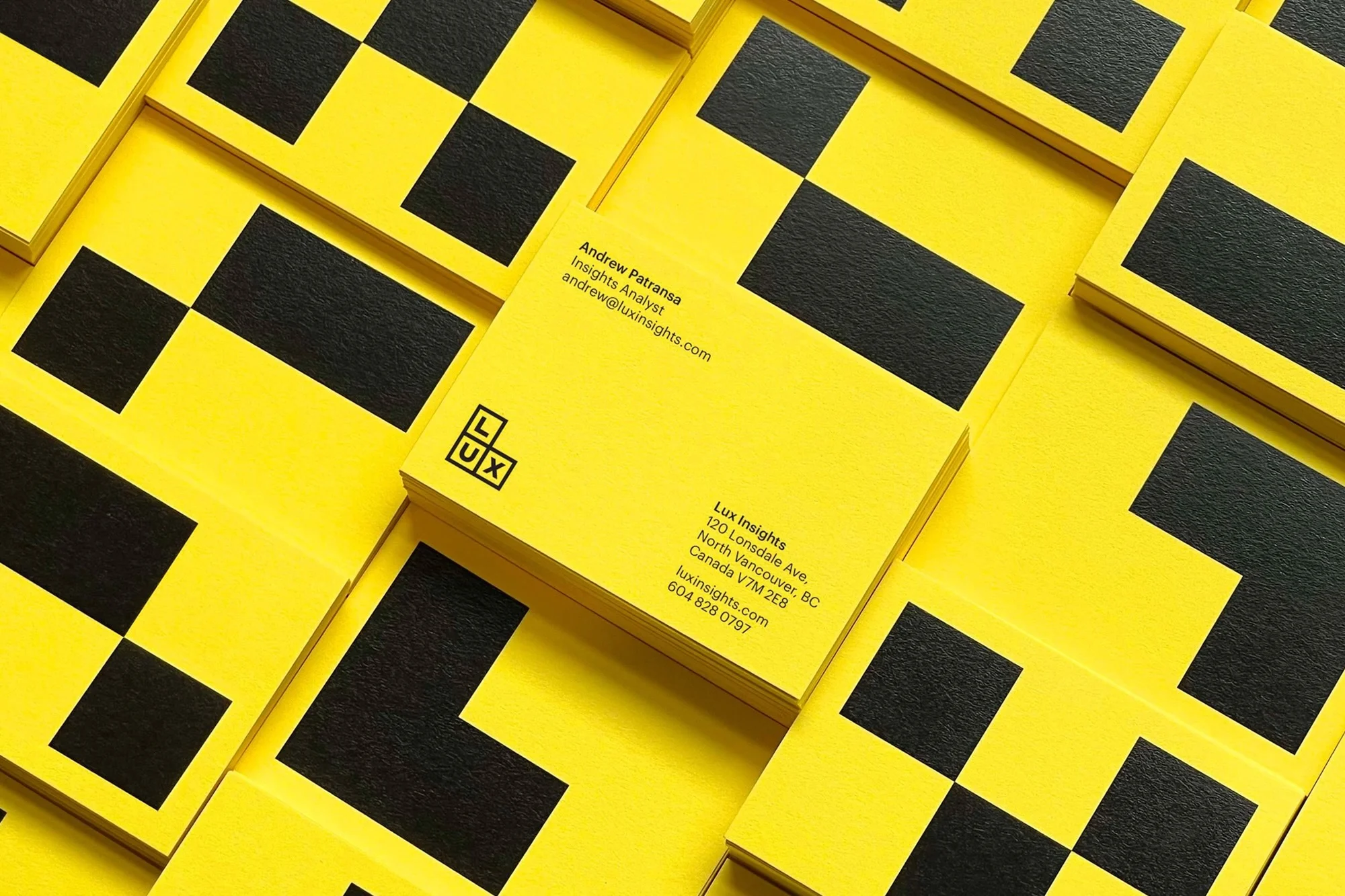 Stack of bright yellow business cards with a black geometric design and company logo on a yellow background. Branding and marketing.
