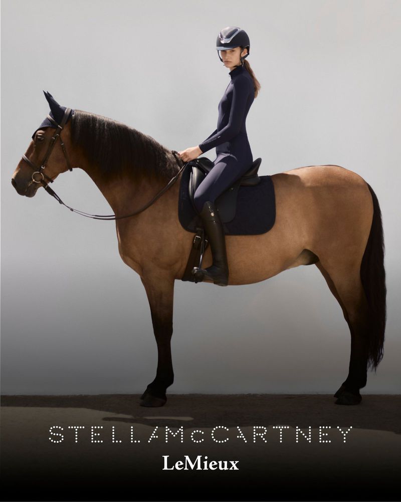 A woman in equestrian apparel rides a tan horse in a studio shot featuring the Stella McCartney LeMieux brand logo on a grey background.