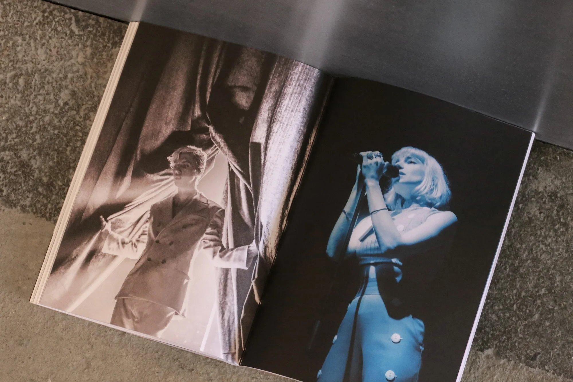 Open magazine spread with images of performers: one an androgynous performer in a suit; the other, a singer in concert lights.