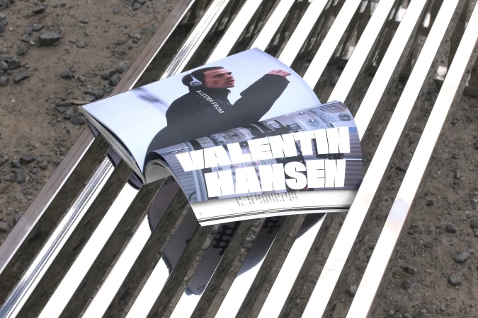 Open magazine on a metal bench features an image of a man in headphones and the name 'Valentin Hansen' in bold white letters.