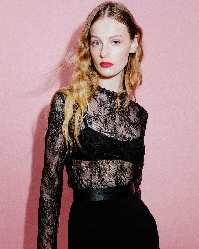 Portrait of a blonde woman in a black lace top against a pink background, showcasing fashion, beauty, and portrait photography.