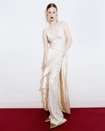 Model in white satin slip dress standing against a white wall on a dark red floor for Alberta Ferretti