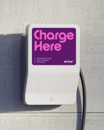 White electric vehicle charging station mounted on a textured grey concrete wall with purple branding.