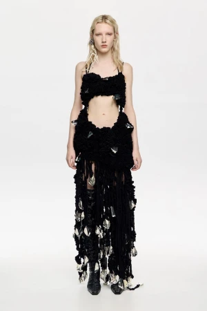 Full-length shot of a fair-skinned adult female fashion model in a black two-piece outfit with fringe and crystal accents in a photo studio.