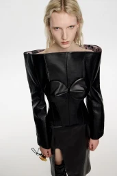 Model wearing a structured black leather off-the-shoulder top against a plain white background for Bimba y Lola
