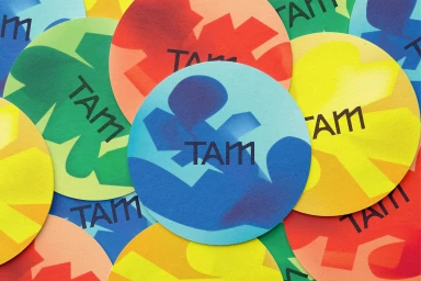 Colorful overlapping circular stickers featuring the TAM brand logo in bold typography