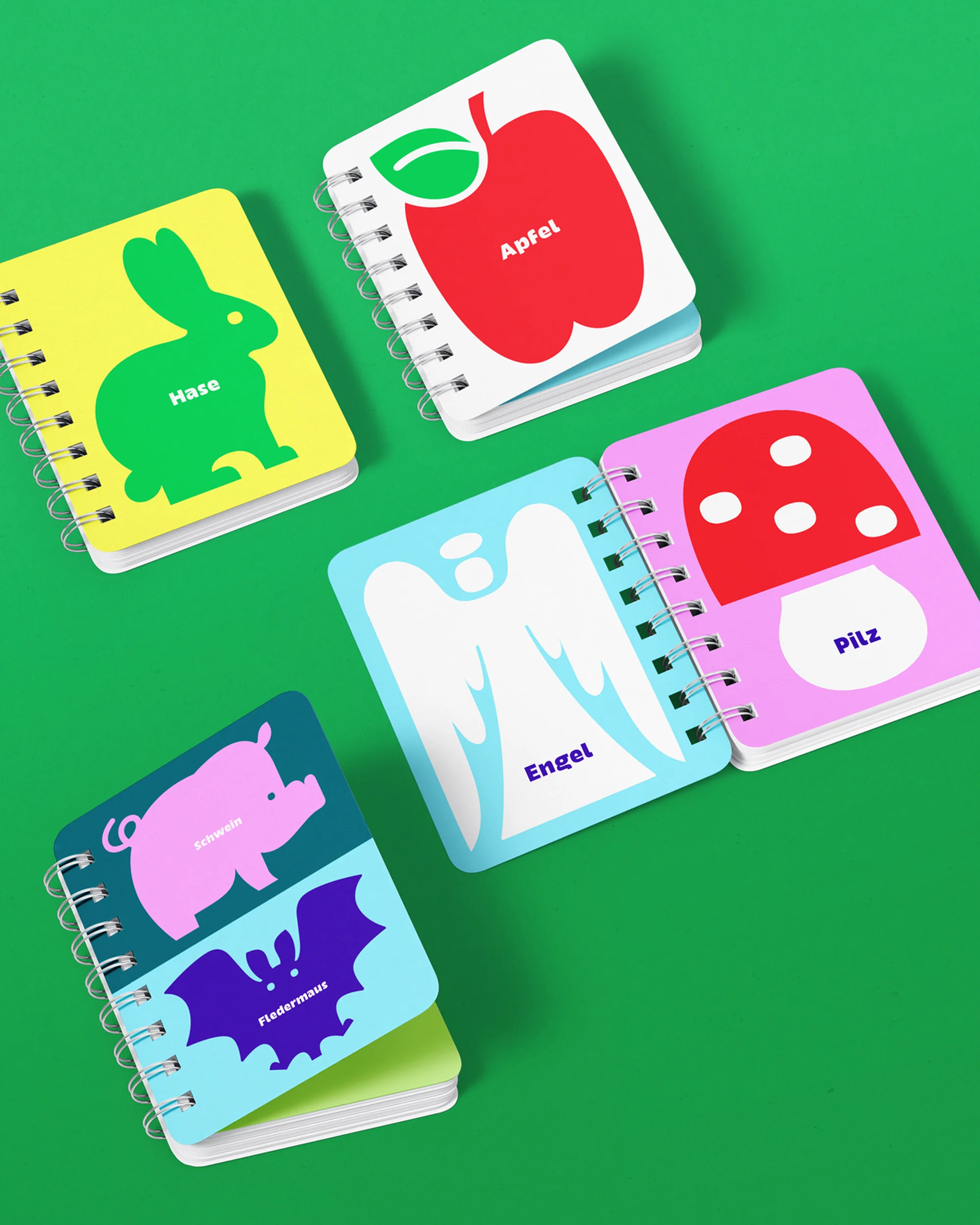 Illustrative learning cards featuring an apple, rabbit, angel, mushroom, pig, and bat, laid out on a green surface.