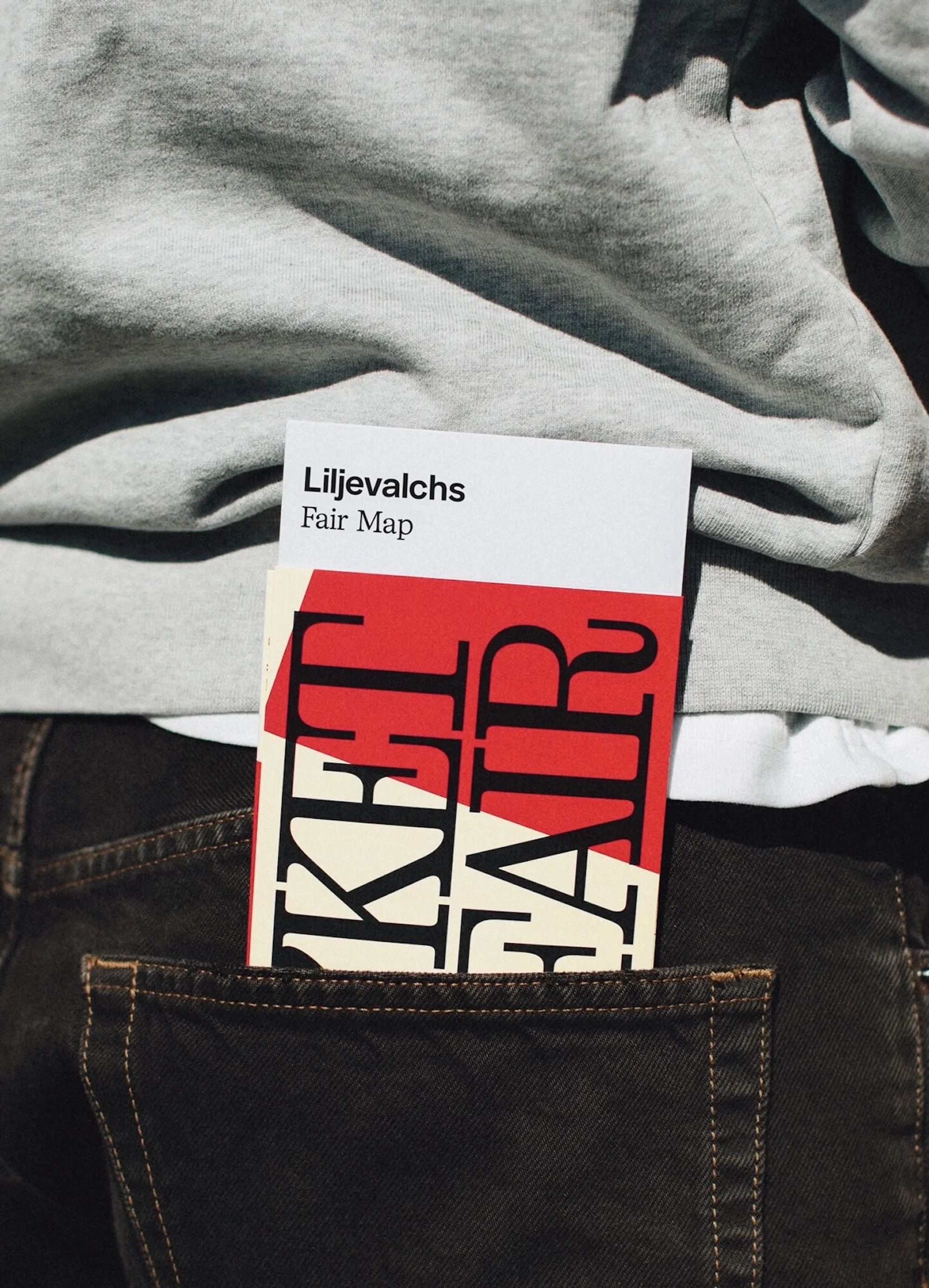 Close-up of Liljevalchs Fair Map sticking out of a person's back pocket, with a light grey sweatshirt visible above. 