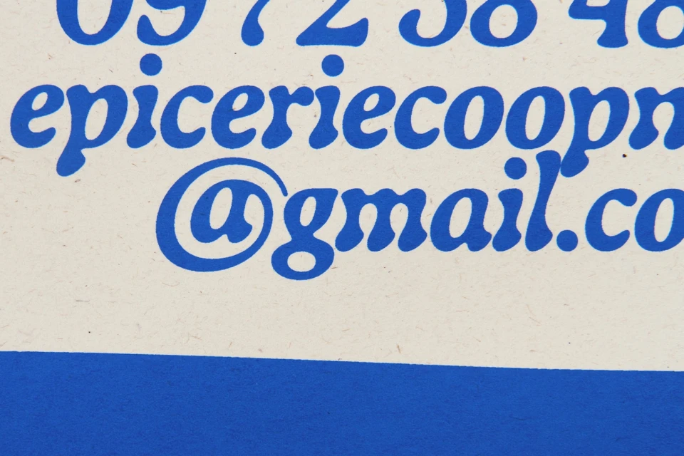 Close-up of blue text on an off-white background, including a phone number, email address, and the word 'epiceriecoop'