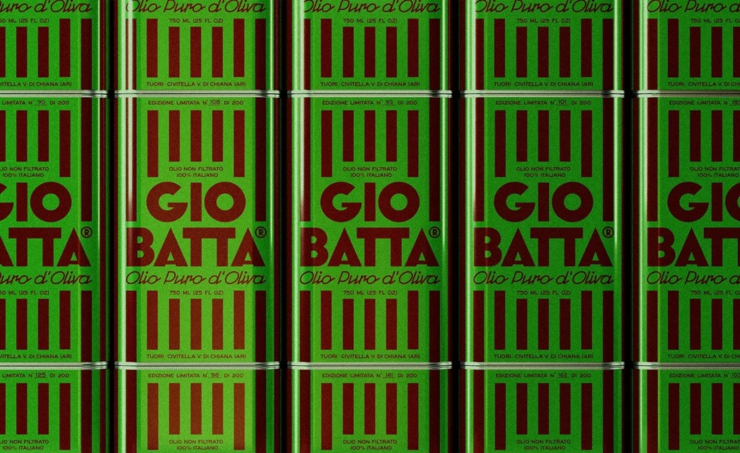 Multiple green tins of Gio Batta Olio Puro d'Oliva stacked in rows, featuring red vertical stripes and Italian text labels.