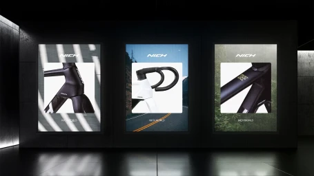 Three vertical glowing display panels showcasing bicycle brand identity graphics and product details against dark walls