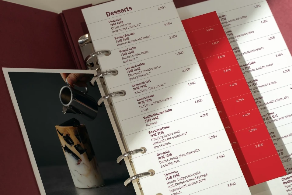 Dessert and coffee menu featuring tiramisu with coffee and a drink being poured from a silver container in a cafe setting.