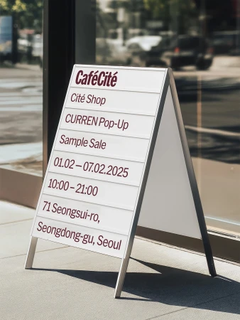 A-frame sign in front of a glass storefront. The sign advertises CaféCité, Cité Shop, and a CURREN Pop-Up store in Seoul.