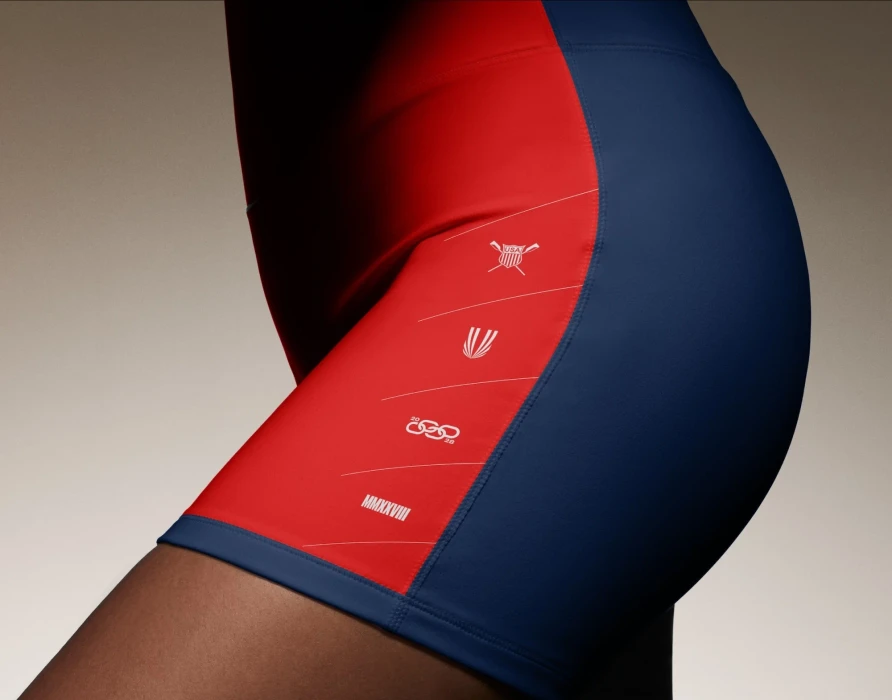 Close-up of an athlete wearing red and blue athletic shorts with white graphic details for the USRowing brand identity.