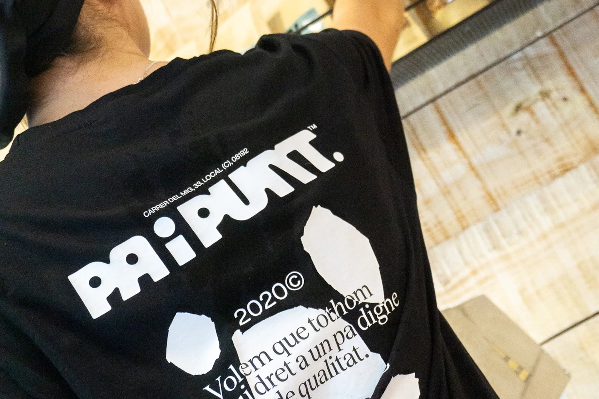 Close-up of a person wearing a black t-shirt with a white graphic design featuring the word 'PAIPUNT' and some text in Catalan.