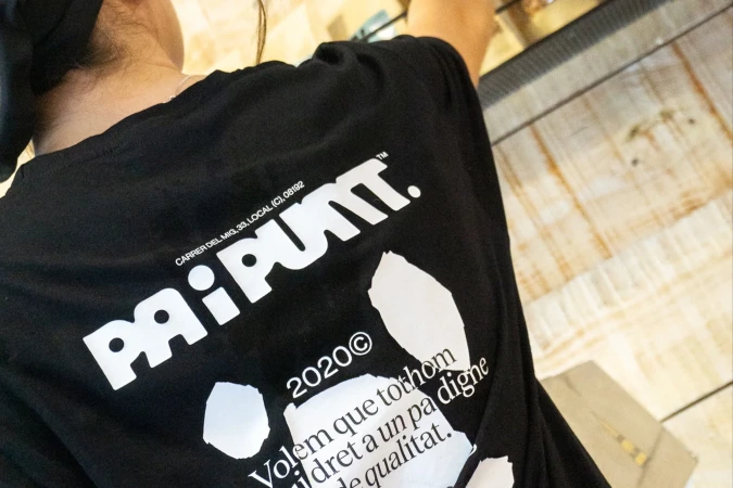 Close-up of a person wearing a black t-shirt with a white graphic design featuring the word 'PAIPUNT' and some text in Catalan.