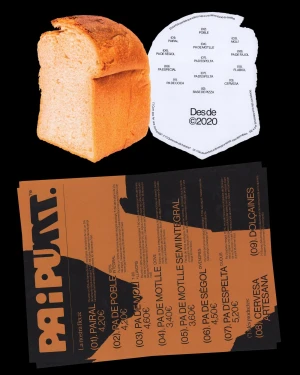 A golden loaf of bread next to a die-cut paper tag and a menu card for Pa i Punt on a solid black background.