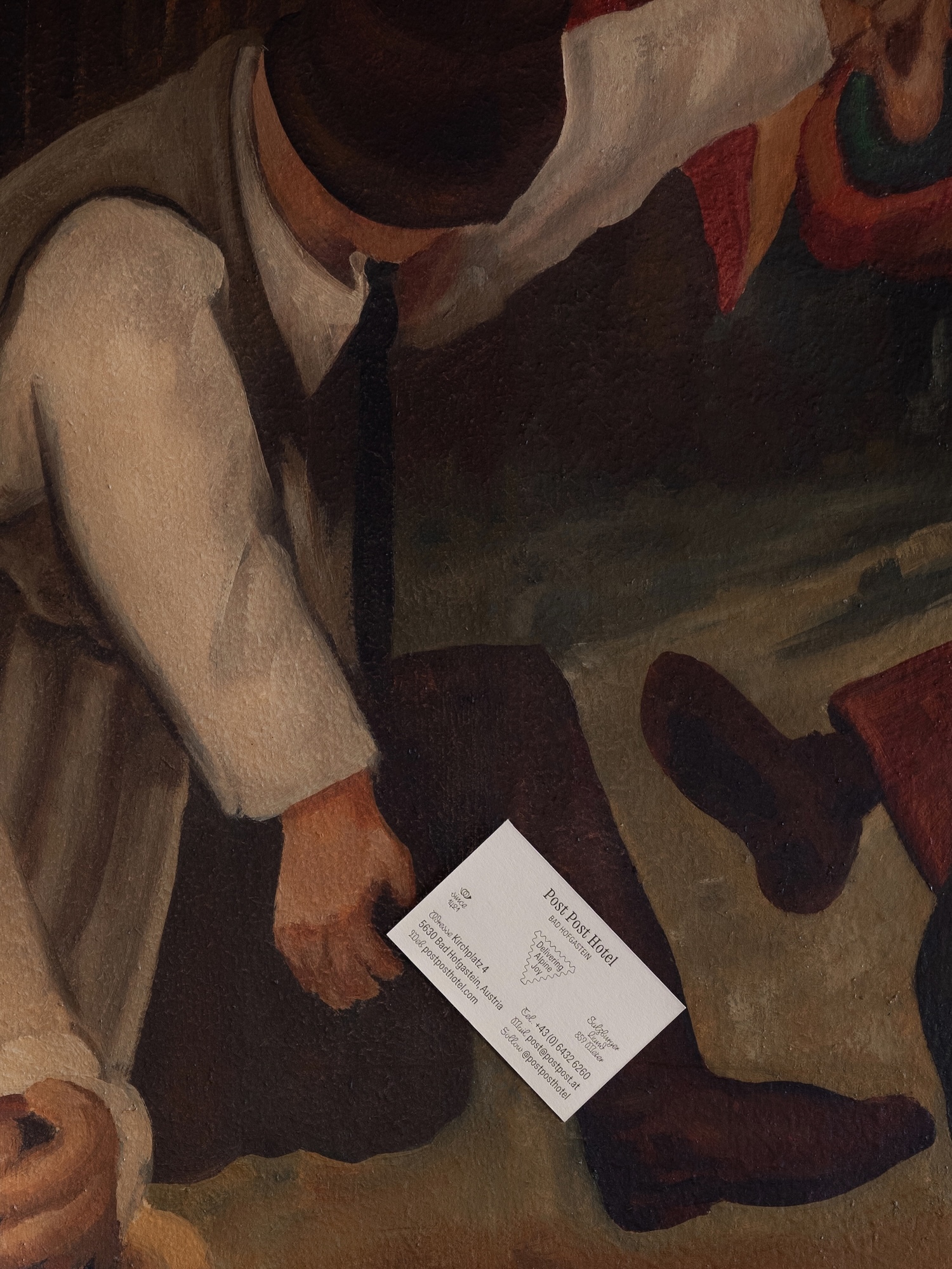 Painting of figures in a landscape with a business card in the foreground displaying text and a logo.