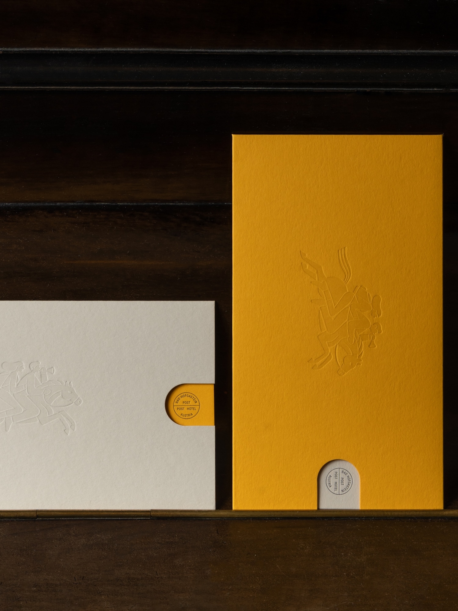 Yellow and white paper cards with embossed designs and circular cutouts rest on a dark wooden surface, showcasing minimalist design.