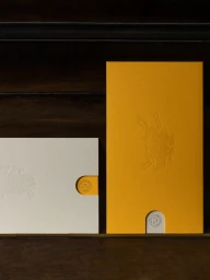 Yellow and white textured paper envelopes with embossed imagery and thumb cuts against a dark background.