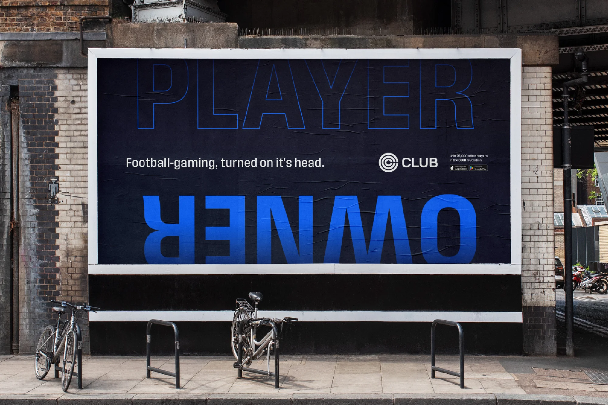 Billboard advertisement for a football gaming app with bicycles parked nearby in an urban setting. Bold blue and white text on a dark background.